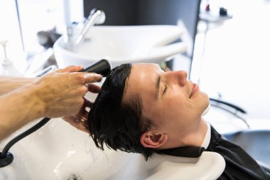 Yakışıklı adam onun saç Kuaför salon içinde yıkanmış olması. Genç adam gözleri ile yatan güzellik salonda kapalı.