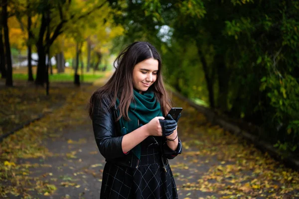 Cep telefonuna kısa mesaj okuma mutlu bir genç kadın portresi.