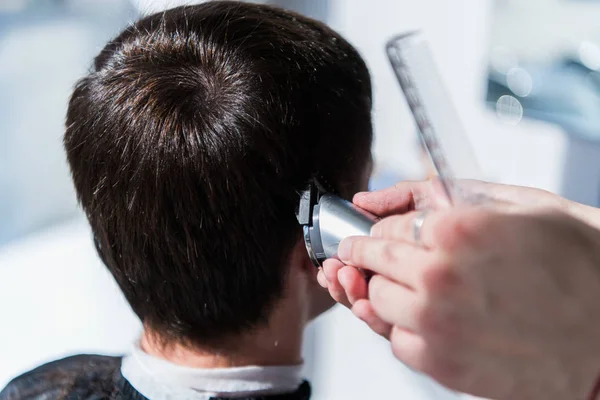 Master snijdt haar van mannen in de kapsalon, Kapper maakt kapsel voor een jonge man — Stockfoto