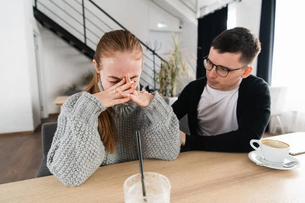 Meeting of a sad woman and a friend or boyfriend trying to comfort her in the cafe