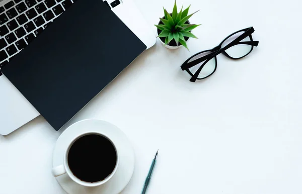 Üstten görünüm alanı laptop, çiçek, fincan kahve, defter, kalem ve gözlük ile çalışma