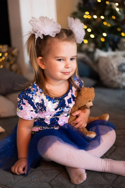 Весела маленька дівчинка сидить у підлозі і тримає пухнасту іграшку — стокове фото
