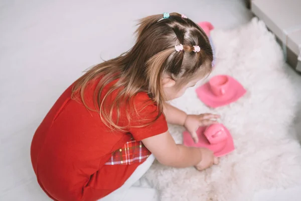 Menina jogar brinquedo bebê pratos em casa — Fotografia de Stock
