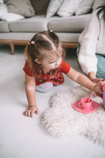 Menina jogar brinquedo bebê pratos em casa — Fotografia de Stock