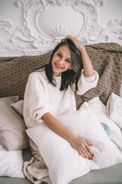 Vintage ev iç çekici esmer kadın. Güzel kadın beyaz sıva duvar arka koltukta oturan beyaz bir kazak modeli