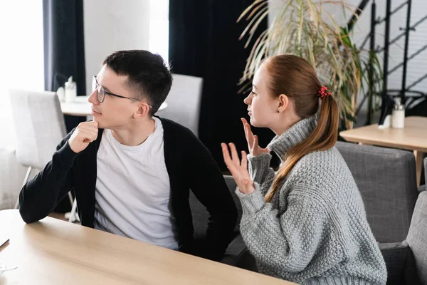 Angry couple arguing sitting on a sofa at the cafe. Man ignores his girlfriend — Stock Photo, Image