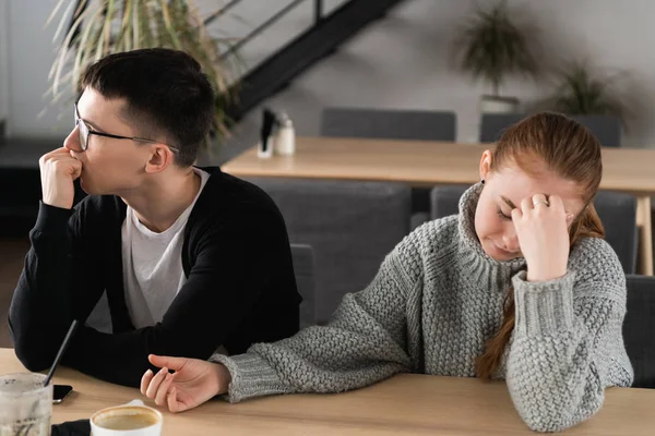 Angry unhappy young couple ignoring not looking at each other after family fight or quarrel, upset thoughtful spouses avoiding talk, sitting silently on couch, having relationship troubles