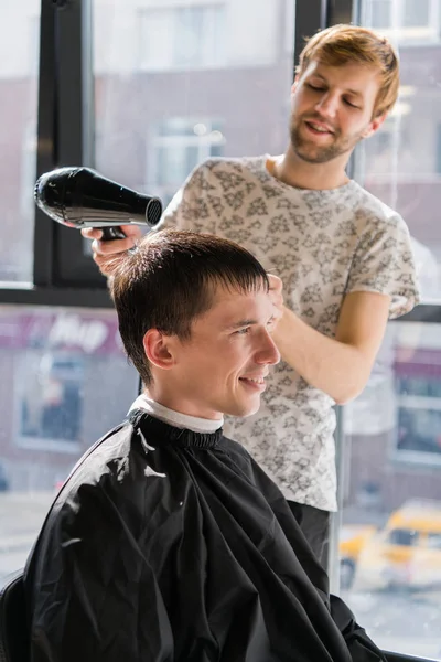 Молодий хіпстер в перукарні, перукарня, що ріже волосся ножицями, сушить. Місце концепції чоловіків — стокове фото
