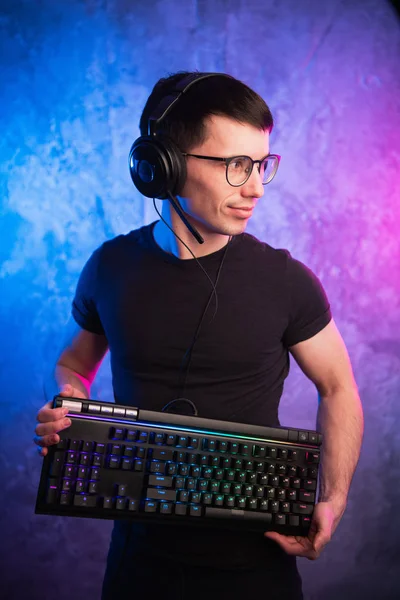 Profesyonel çocuk oyuncu holding klavye üzerinde renkli pembe ve mavi neon oyun duvar yaktı. Oyun oyun kavramı