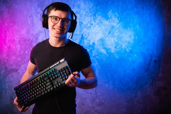 Profesyonel çocuk oyuncu holding klavye üzerinde renkli pembe ve mavi neon oyun duvar yaktı. Oyun oyun kavramı