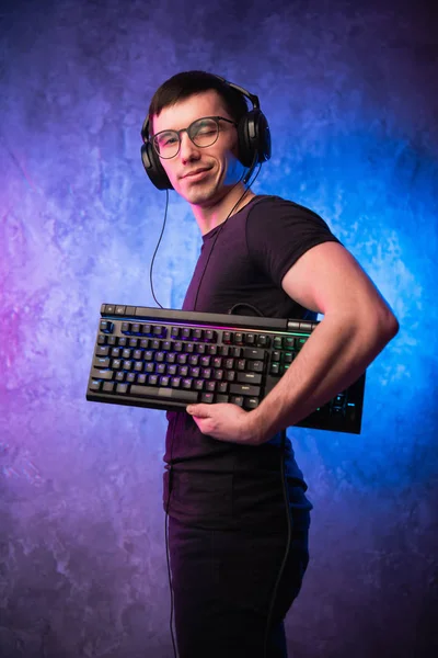 Professional Boy Gamer segurando teclado de jogos sobre colorido rosa e azul neon iluminado parede. Gaming gamers conceito — Fotografia de Stock