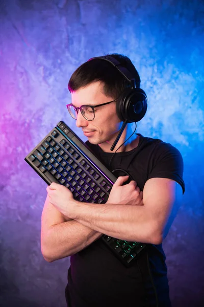 Professional Boy Gamer holding gaming keyboard over colorful pink and blue neon lit wall. Gaming gamers concept — Stock Photo, Image