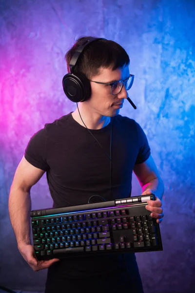 Professional Boy Gamer hospodářství herní klávesnice přes barevné neon růžové a modré osvětlené zdi. Herní hráči koncept — Stock fotografie