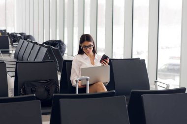Laptop Havaalanı salonunda çalışan casual kadın. Onun uçuş Havaalanı terminalinde bekliyor, sandalyede oturan ve dizüstü bilgisayarda yazarak kadın