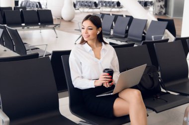 Tafrīh iş. Onu uçuş bir havaalanında beklerken dizüstü bilgisayarda çalışan güzel kadın