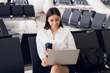 Tafrīh iş. Onu uçuş bir havaalanında beklerken dizüstü bilgisayarda çalışan güzel kadın