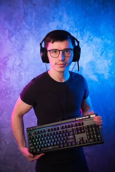 Professional Boy Gamer hospodářství herní klávesnice přes barevné neon růžové a modré osvětlené zdi. Herní hráči koncept — Stock fotografie