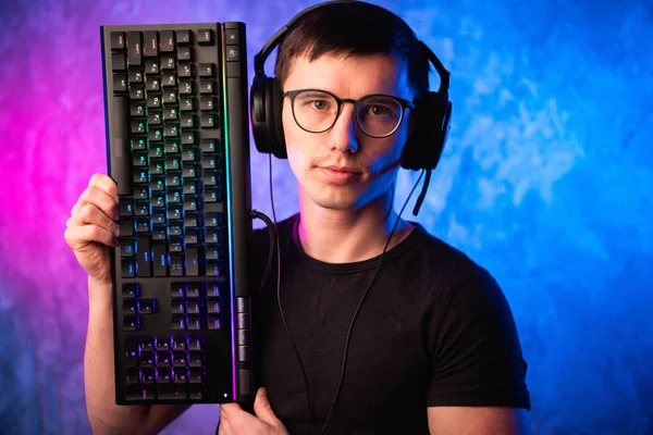 Technologie, Cyberspace, Programmierung und People-Konzept - Hacker mit Headset und Brille mit Tastatur über Neonwand — Stockfoto