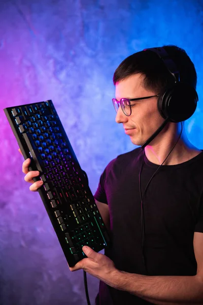 Professional Boy Gamer hospodářství herní klávesnice přes barevné neon růžové a modré osvětlené zdi. Herní hráči koncept — Stock fotografie