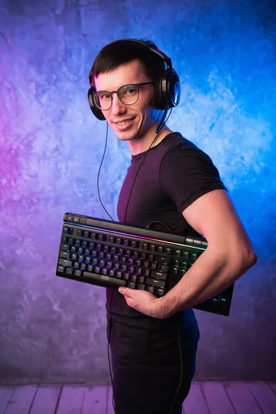 Bilgisayar nerd yaktı, pembe ve mavi renkli neon duvarın üzerinden klavye ile