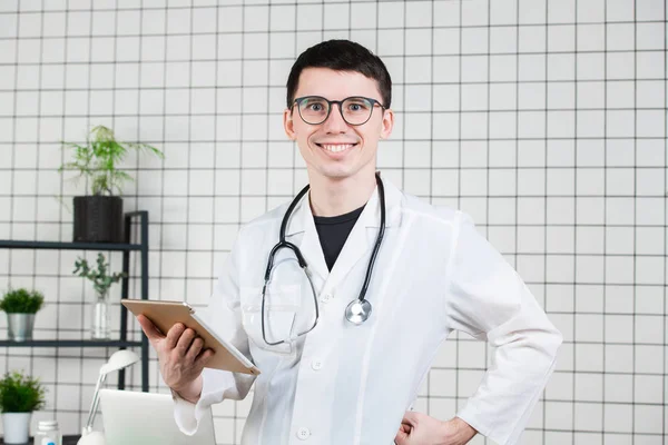 잘생긴 젊은 남성 의사 태블릿 컴퓨터를 사용 하 여 미소. 의학 개념에 기술 — 스톡 사진