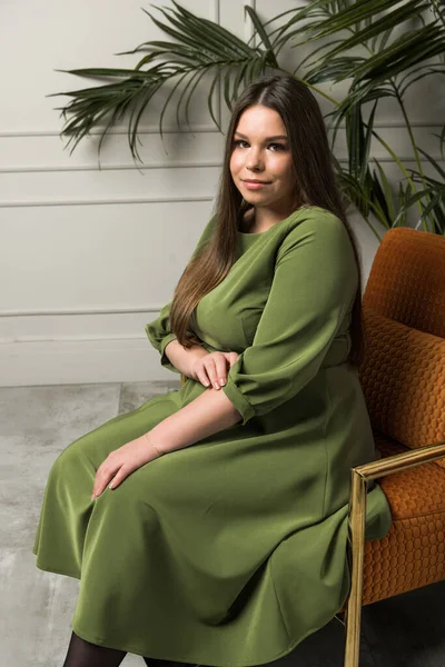 Stüdyoda bir sandalyede oturan gece elbisesi içindeki güzel genç bayan.