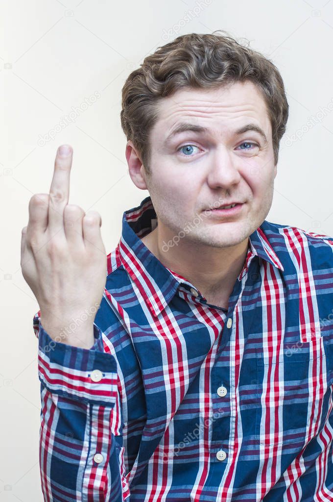 Portrait of young funny, venturesome man showing hand sign obscene gesture middle finger on white background.