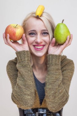 Meyve ve sebze insanlarla. Sağlıklı bir yaşam tarzı. Kafasında elma armut ve muz gösteren genç gülümseyen kadın.