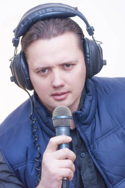 Mikrofon ve kulaklık beyaz arka plan üzerinde genç beyaz elbise adam yorumcu portresi