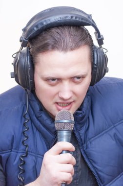 Mikrofon ve kulaklık beyaz arka plan üzerinde genç beyaz elbise duygusal adam yorumcu portresi