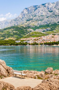 Yaz deniz manzarası. Ön buzlu, canlı Adriyatik Denizi suları orta yol ve özel evler, çam ağaçları, restoranlar ve barlarla dolu bir kıyı şeridi beyaz bankta