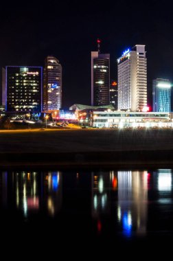 Vilnius, Litvanya - 9 Mart 2014. Gece cityscape görünümünü Neris Nehri, şehir merkezindeki bussiness binalar, bankalar, oteller, casino, alışveriş merkezleri ve diğer bölgelerinde yeni riverside Vilnius.