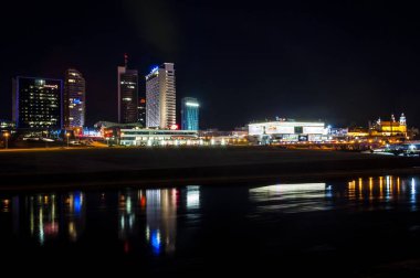 Vilnius, Litvanya - 9 Mart 2014. Gece cityscape görünümünü Neris Nehri, şehir merkezindeki bussiness binalar, bankalar, oteller, casino, kiliseler, alışveriş merkezleri ve diğer bölgelerinde yeni riverside
