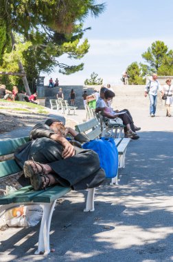 Avignon, Fransa - 24 Temmuz 2011: Evsiz adam Avignon Festivali kapalı sırasında tezgah altında bıçakla Eski kentte oudoors uyuyor. Ona yakın insanlar istirahat, oturan, tarafından yürüyüş.