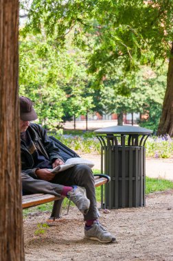 Bremen, Germany - June 12, 2011: Man sitting on the bench and reading newspaper on fresh air outdoors in cozy Wallanlagen park in Bremen, Germany