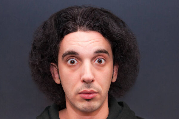 Шокированный молодой человек с большими открытыми глазами и пушистой прической
