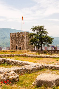 Skopje, Makedonya - 10 Haziran 2013: Antik taş kule ile ön plan üzerinde çiçek kırmızı ortak haşhaş ve ünlü Millennium çapraz anıt Vodno Dağı'nda büyüyen eski kale bir parçası olarak