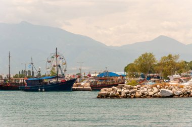 Paralia, Greece - June 13, 2013: Sea stones marina, touristic and fishermen boats and ships in small bay, city attractions and Olympus mount on the background clipart