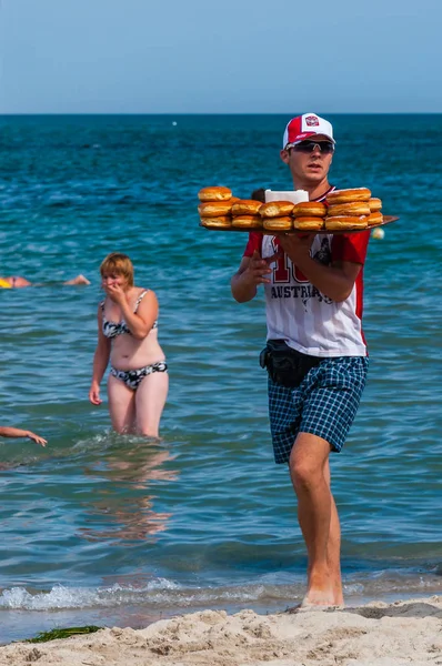希腊帕拉利亚 男子拿着照片 在休息的游客之间的海滩上散步时 在上出售甜甜的甜甜圈 季节性海滩度假村业务 — 图库照片