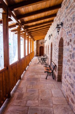 Meteora, Yunanistan - 16 Haziran 2013: Courtyard balkon, galerileri Ahşap korkuluk ve çatılar, banklar ile büyük Meteoron manastırı Yunanistan'da Meteora dağlar üzerinde duvar ve kemer kapıları yakınındaki