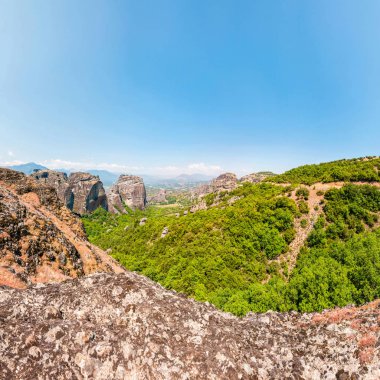 Manzaralı panoramik manzaralı Meteora kaya oluşumları kayalıklarla ve canlı yeşil bitki örtüsü, bitkiler ve ağaçlar Yunanistan çevrili tepeleri