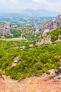 Meteora, Yunanistan - 16 Haziran 2013: Panoramik manzaralı Meteora manzara kaya oluşumları üzerinde Saint Nicholas Anapafsas Manastırı cliff ve dağlar dizi ve vadiler arka planda
