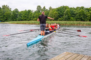 Trakai, Litvanya - 26 Temmuz 2013: bir turist nasıl sekiz kürek Galve göl sularının eserlerinde tekne öğretim eğitmen koç. Sekiz rekabet kürek Sporda kullanılan bir kürek tekne olduğunu.