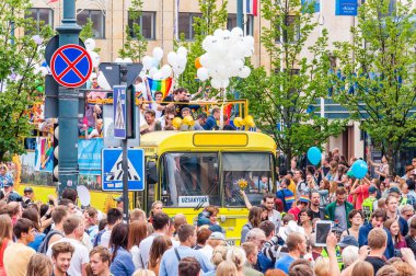 Vilnius, Litvanya - 27 Temmuz 2013: Pride parade olay eylem. Gökkuşağı barış bayrakları ile göstericiler tam beyaz balonlarla süslenmiş sarı açık üst otobüs çevreleyen izleyici kalabalık