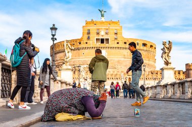 Rome, İtalya - 17 Kasım 2018: Ponte Sant'Angelo, Hadrian köprü Castel Sant'Angelo, arka plan üzerinde kutsal melek kale grubu yürümekten tam üzerinde diz sadaka isteyen dilenci kadın
