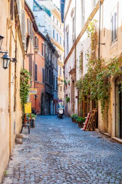 Rome, İtalya - 18 Kasım 2018: Rahat dar Antik Ortaçağ Old Town kaldırım taşı yeşil büyümüş cepheler, küçük işletmeler, Roma, İtalya Park edilmiş motorlu bisikletler ile sokak