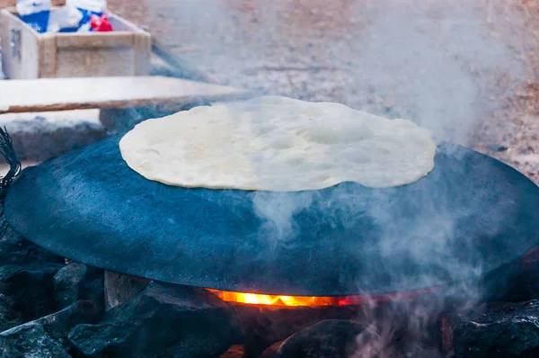 Traditional bedouin cake cooking on round semi sphere metal plate on fire in Eilat, Israel