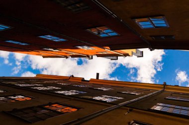 Aşağıdan bir rahat dar Ortaçağ sokak sarı turuncu kırmızı binaları cephe Gamla Stan'da, eski Stokholm şehir, İsveç arka plan üzerinde parlak mavi gökyüzü ile çatılarda görüntülemek