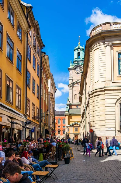 Acogedora calle medieval con gente que camina, negocios que trabajan, fachadas de edificios naranjas amarillas en Gamla Stan, casco antiguo de Estocolmo, Suecia —  Fotos de Stock