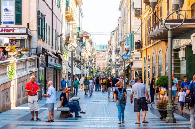 Sanremo, İtalya'da antik ortaçağ Old Town sokak tarafından yürüyen insanlar.